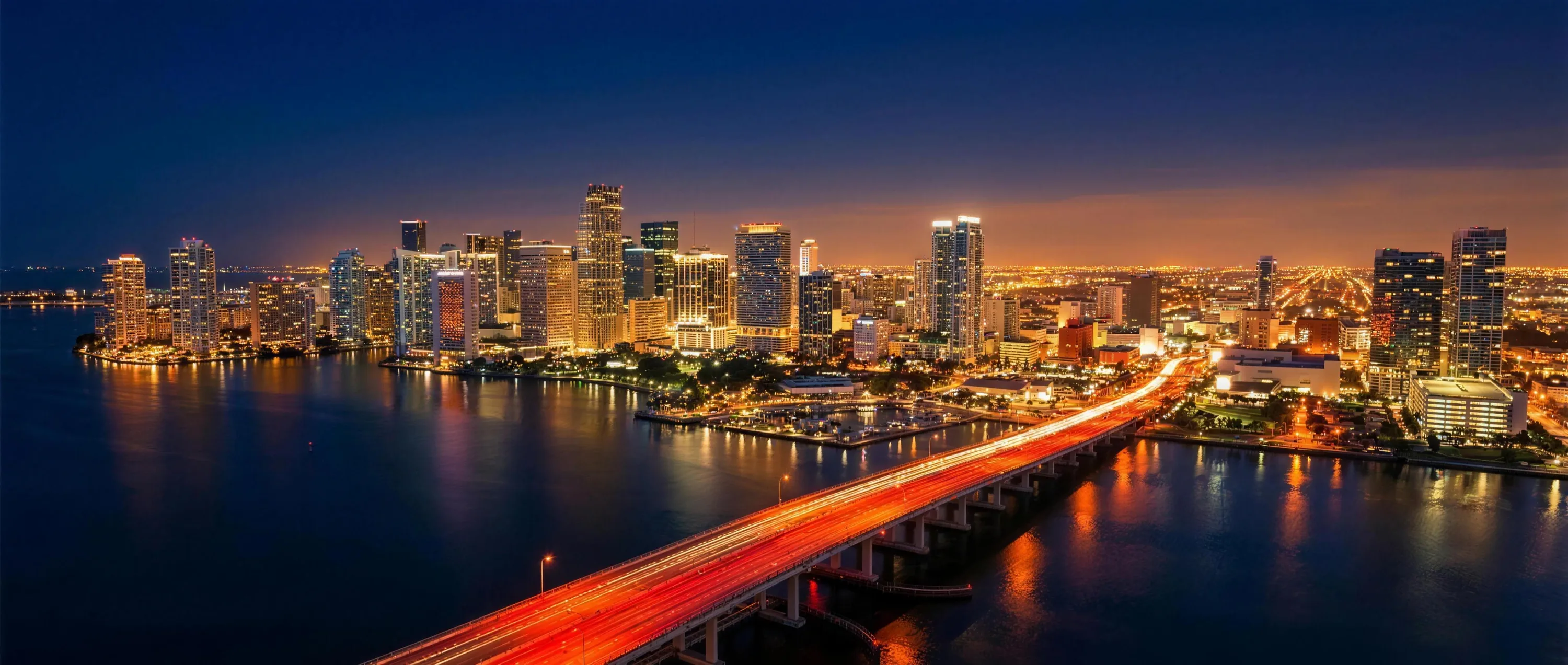 Miami at night — causeway bridge into downtown with a red light trail